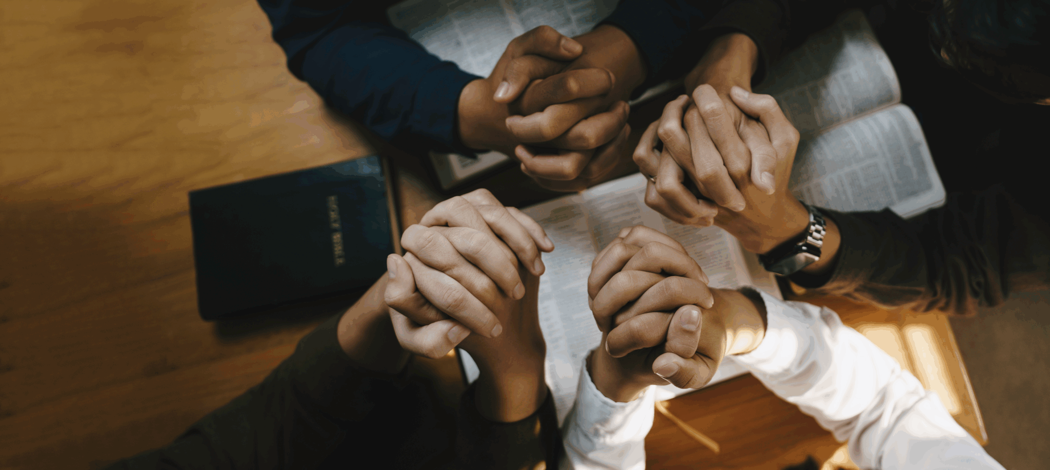People praying together with clasped hands.