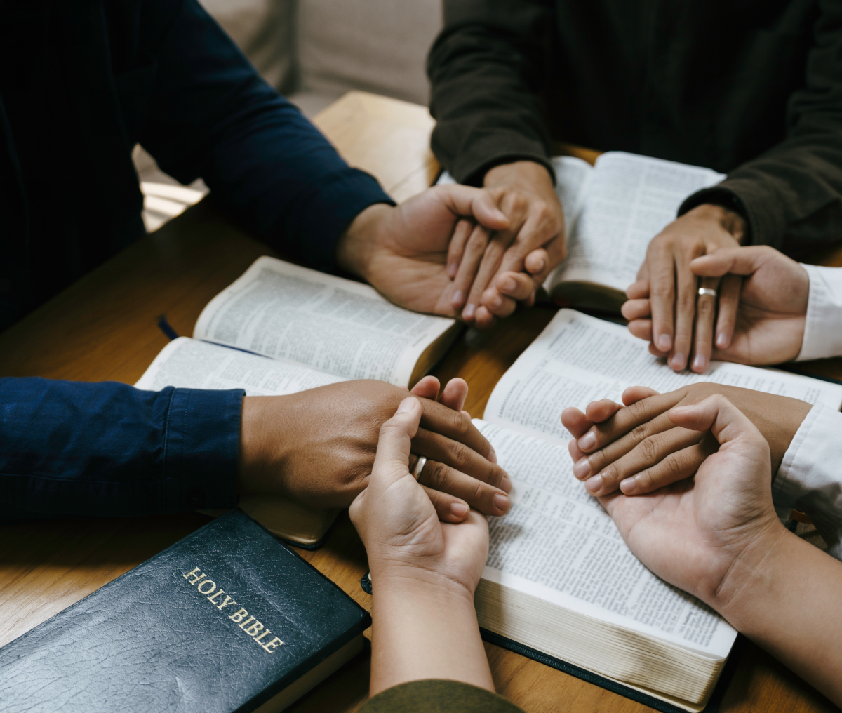 Praying hands with Bible on table