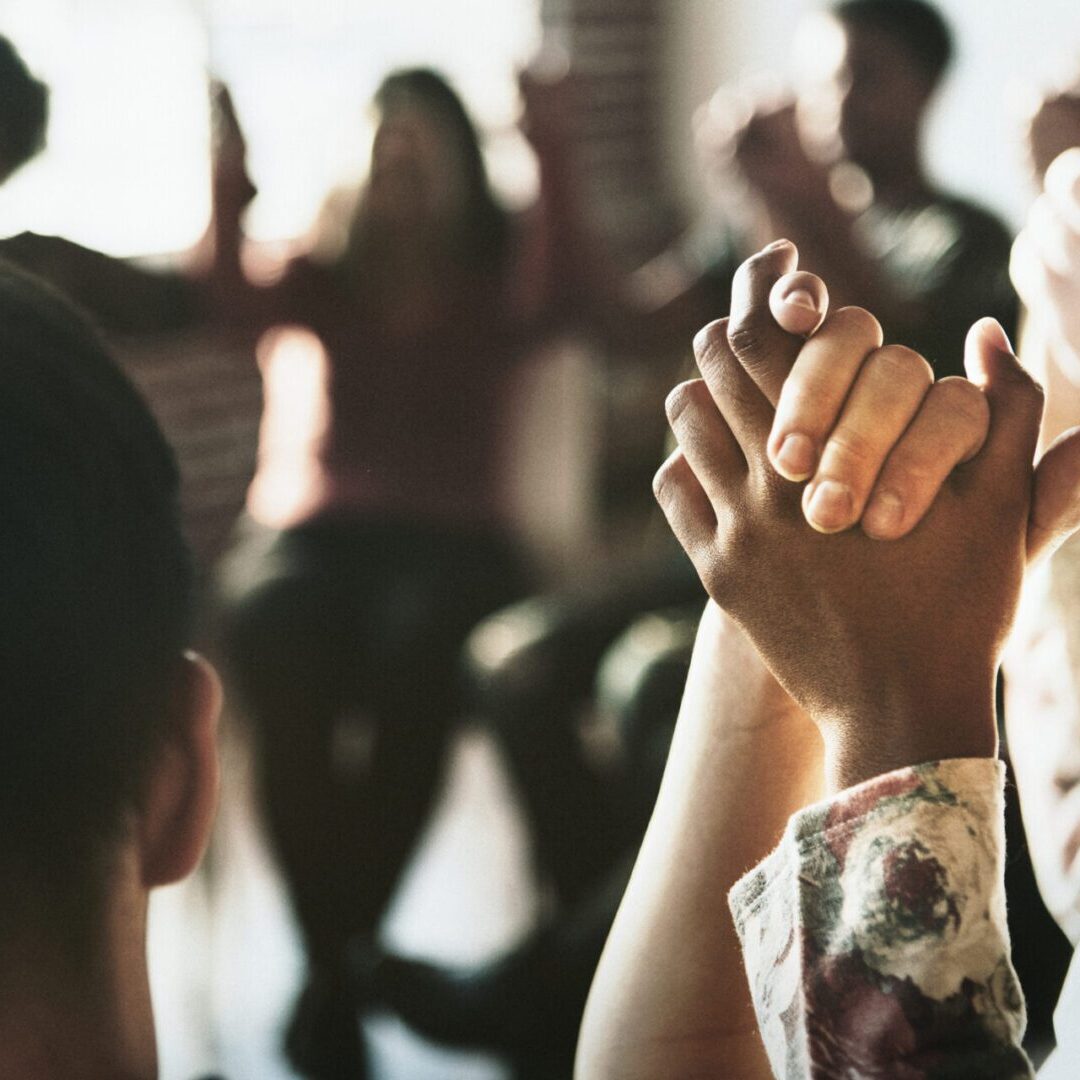 Group of diverse people holding hands up in the air